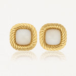 Paire de boucles d'oreilles carrées dorées, à bord torsadé, avec une pierre centrale blanche nacrée.