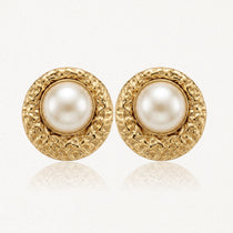 Paire de boucles d'oreilles rondes dorées, perle blanche nacrée au centre, cadre texturé.