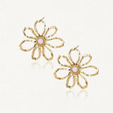 Deux boucles d'oreilles fleur en acier inoxydable doré avec des pétales ajourés et un cabochon central en nacre rose pâle.