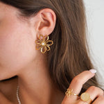 Boucle d'oreille fleur stylisée de 3cm en acier inoxydable doré avec centre en nacre, portée par une femme.