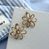 Paire de boucles d'oreilles fleurs ajourées en acier inoxydable doré, avec un cœur en nacre blanche et des pétales martelés.