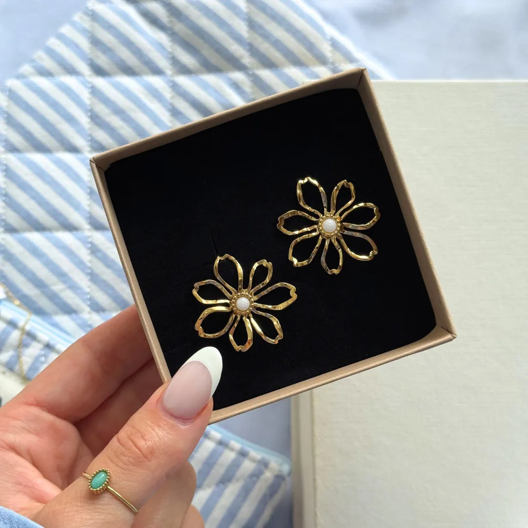 Deux boucles d'oreilles en acier inoxydable doré, en forme de fleurs texturées, avec un cœur en nacre blanche, dans une
