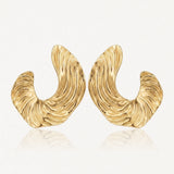 Paire de boucles d'oreilles dorées, épaisses et incurvées, avec une texture striée rappelant des vagues.