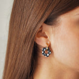 Boucles d'oreilles Lena en acier inoxydable doré avec un pendentif en forme de fleur noire à pois blancs