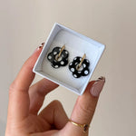 Boucles d'oreilles LENA en acier inoxydable doré avec motif de fleur noire à pois blancs dans une petite boîte blanche