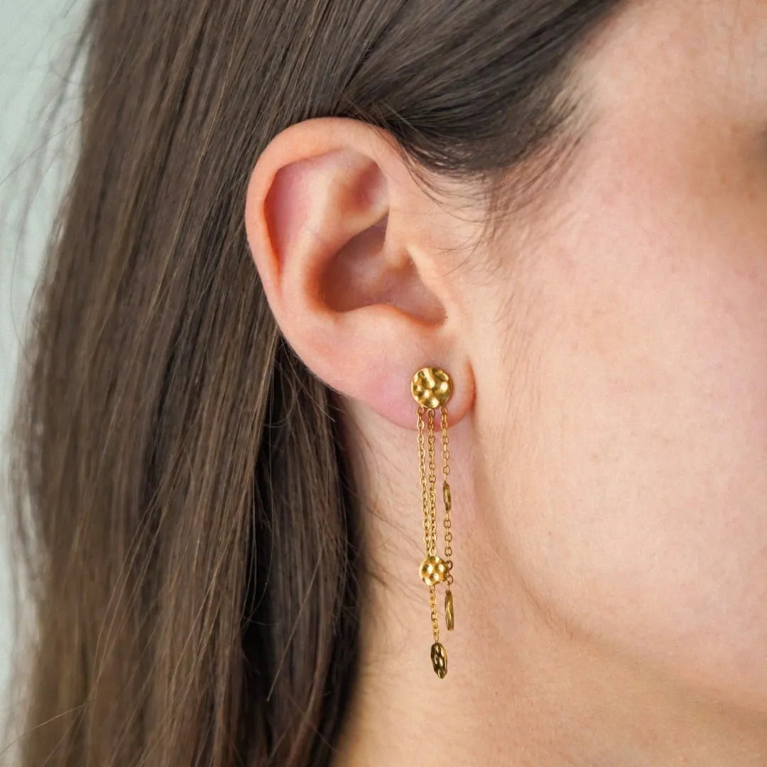 Boucle d'oreille pendante en acier inoxydable doré, avec un clou rond martelé et trois chaînes à petits disques martelés.