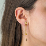 Boucle d'oreille pendante en acier inoxydable doré, avec un clou rond martelé et trois chaînes à petits disques martelés.