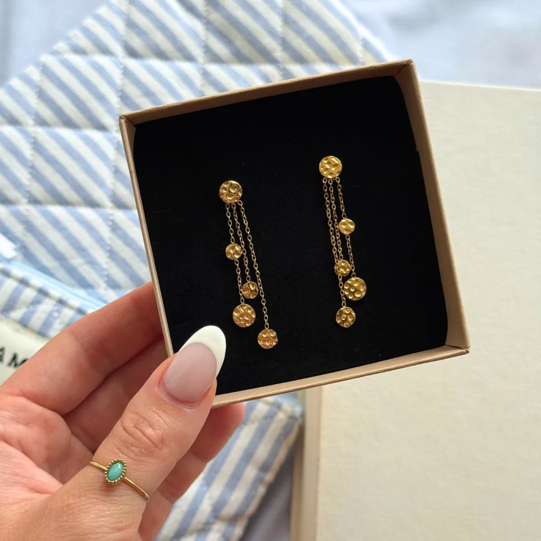 Boucles d'oreilles pendantes de 5 cm en acier inoxydable doré, ornées de chaînes et disques martelés, dans un écrin.