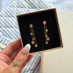 Boucles d'oreilles pendantes de 5 cm en acier inoxydable doré, ornées de chaînes et disques martelés, dans un écrin.