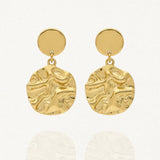 Paire de boucles d'oreilles pendantes en acier inoxydable doré, composées d'un stud rond uni et d'un large pendentif rond martelé irrégulier.