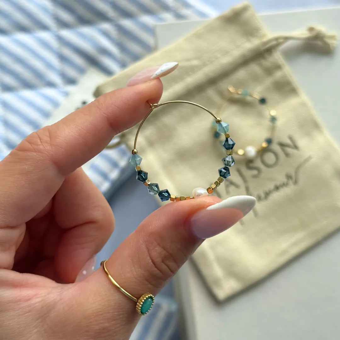 Boucle d'oreille créole en acier inoxydable doré avec des perles blanches et des pierres naturelles bleues facettées. Une