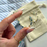 Boucle d'oreille créole en acier inoxydable doré avec des perles blanches et des pierres naturelles bleues facettées. Une