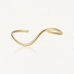 Bracelet jonc ouvert minimaliste en acier inoxydable doré, à double vague asymétrique.