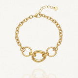 Bracelet en acier inoxydable doré composé de maillons épais et d'une section centrale avec un grand anneau ovale lisse encadré de deux anneaux ronds texturés. Fermoir mousqueton et chaînette d'extension.