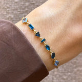 Bracelet Blair en acier inoxydable doré avec des strass en zirconium de différentes formes et teintes de bleu