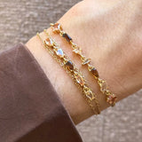 Bracelet Blair en acier inoxydable doré orné de strass en zirconium de différentes formes et teintes sur un poignet