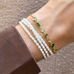 Bracelet Blair en acier inoxydable doré avec strass en zirconium verts et transparents porté avec des perles blanches