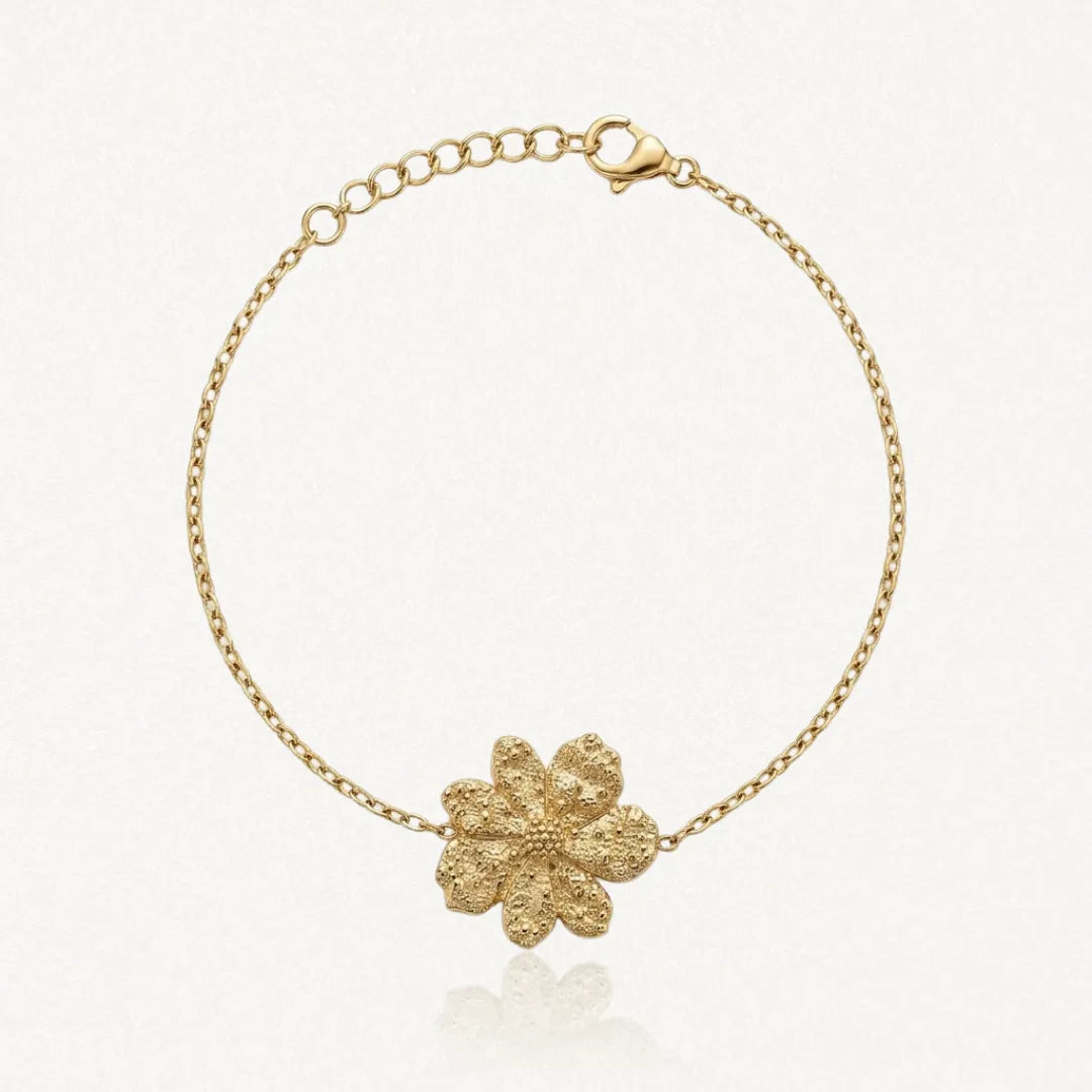 Bracelet fin en acier inoxydable doré avec un pendentif fleur texturé et une chaînette réglable.