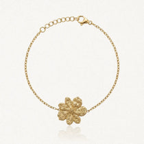 Bracelet fin en acier inoxydable doré avec un pendentif fleur texturé et une chaînette réglable.