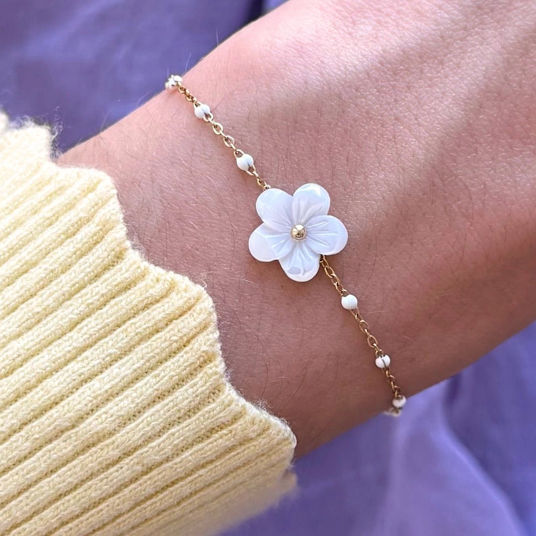 Bracelet doré en acier inoxydable, fine chaîne avec fleur blanche en nacre, cœur doré et petites perles blanches.