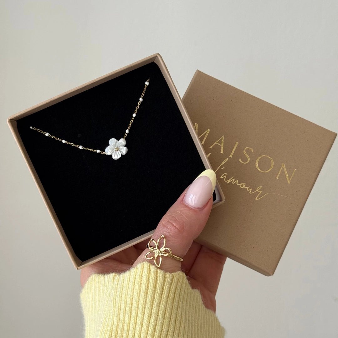 Bracelet en acier inoxydable doré, orné d'une fleur nacre blanche et de perles fines, dans son écrin Maison l'amour.