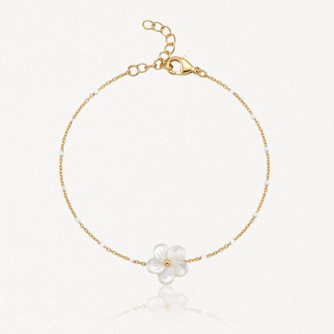 Bracelet en chaîne dorée avec petites perles blanches et un pendentif fleur en nacre à cinq pétales, centre doré. Fermoir