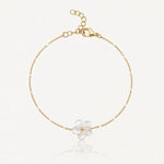 Bracelet en chaîne dorée avec petites perles blanches et un pendentif fleur en nacre à cinq pétales, centre doré. Fermoir