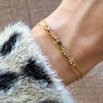 Bracelet double chaîne en acier inoxydable doré, orné de zircons champagne et marron, porté sur un poignet.
