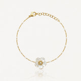 Bracelet chaîne fine dorée agrémentée de perles blanches. Fleur en nacre avec diamant. Fermoir mousqueton doré.
