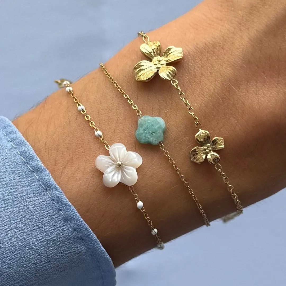 Trois bracelets fins en acier inoxydable doré, l'un avec fleur de nacre et perles, un autre avec trèfle en amazonite, et un
