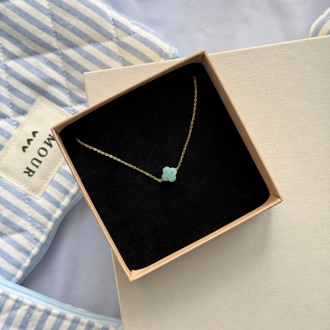 Bracelet fin trèfle en acier inoxydable doré et amazonite, présenté dans un écrin beige à l'intérieur noir.