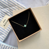 Bracelet fin trèfle en acier inoxydable doré et amazonite, présenté dans un écrin beige à l'intérieur noir.