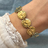 Bracelet doré maillons ronds martelés et embossés, porté sur poignet féminin, manche dentelle et fond jean bleu.