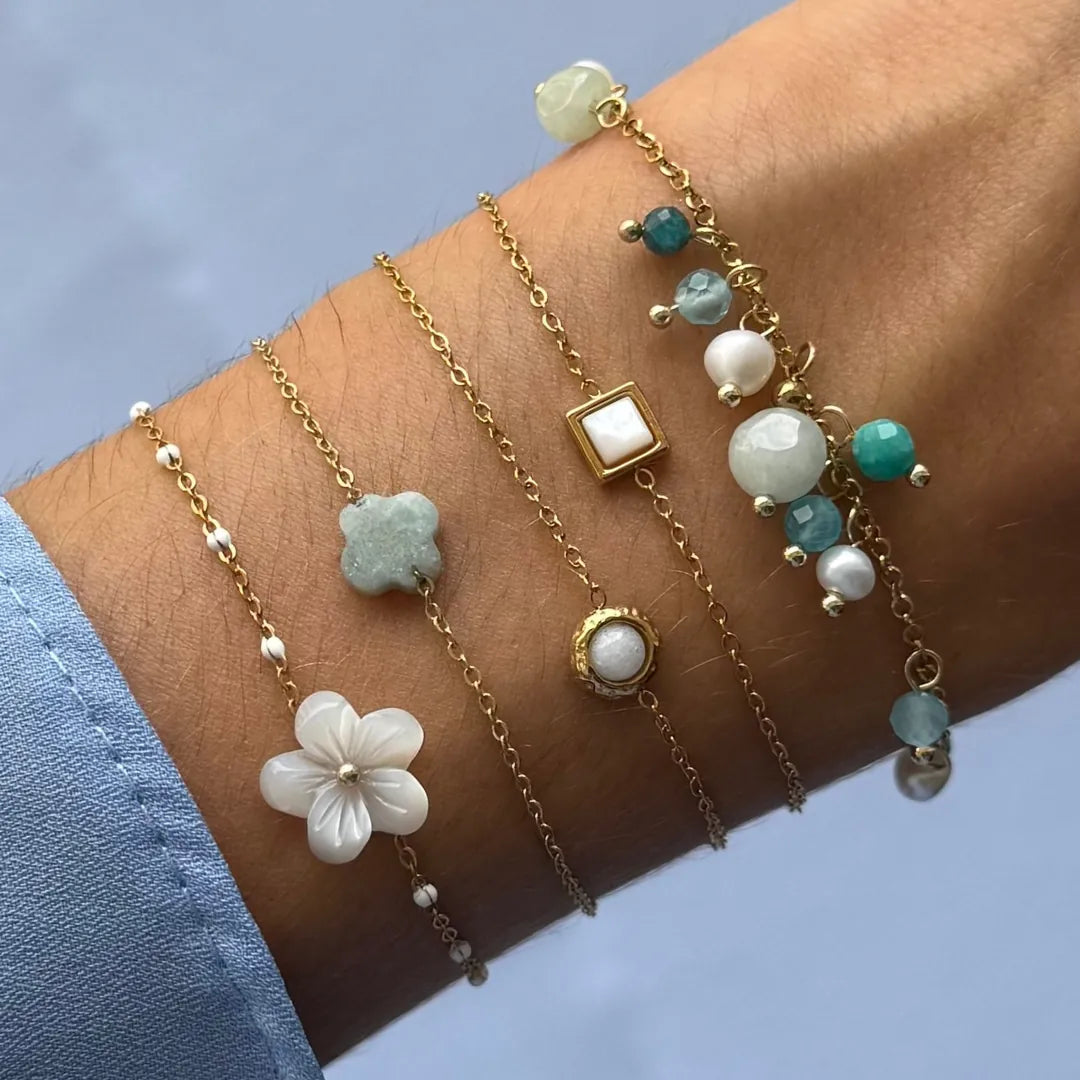 Stack de bracelets en acier inoxydable doré et diverses pierres naturelles, dont un bracelet carré en Jade Blanc sur un