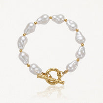 Bracelet en acier inoxydable doré avec de grandes perles baroques blanches et un fermoir toggle martelé.