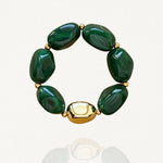 Vue de face sur fond blanc d'un bracelet élastique composé de perles vertes effet pierre et d'une grosse perle dorée lisse.