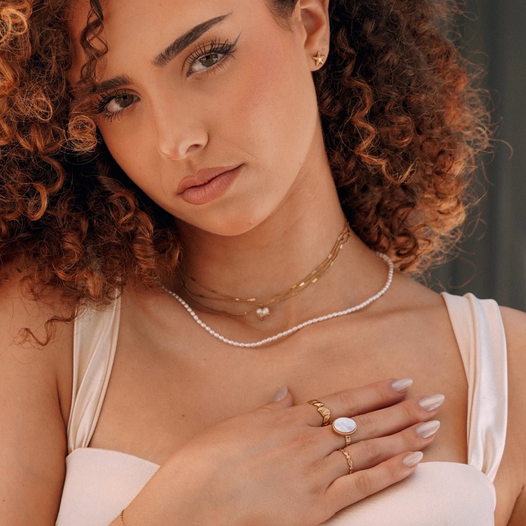 Bracelet chaîne fin doré en acier inoxydable au poignet d'une femme.