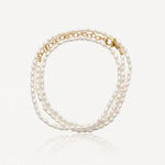 Bracelet à trois rangs de petites perles ovales blanches, avec fermoir et chaîne d'extension dorés.