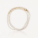 Bracelet à trois rangs de petites perles ovales blanches, avec fermoir et chaîne d'extension dorés.