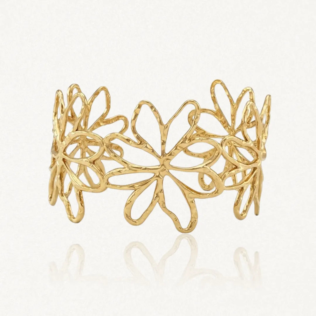 Bracelet jonc en acier inoxydable doré, avec un motif ajouré de fleurs dont la surface est texturée. Sur fond clair.