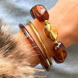 Vue latérale du bracelet à grosses perles porté avec un manteau en fausse fourrure, style chic hivernal.