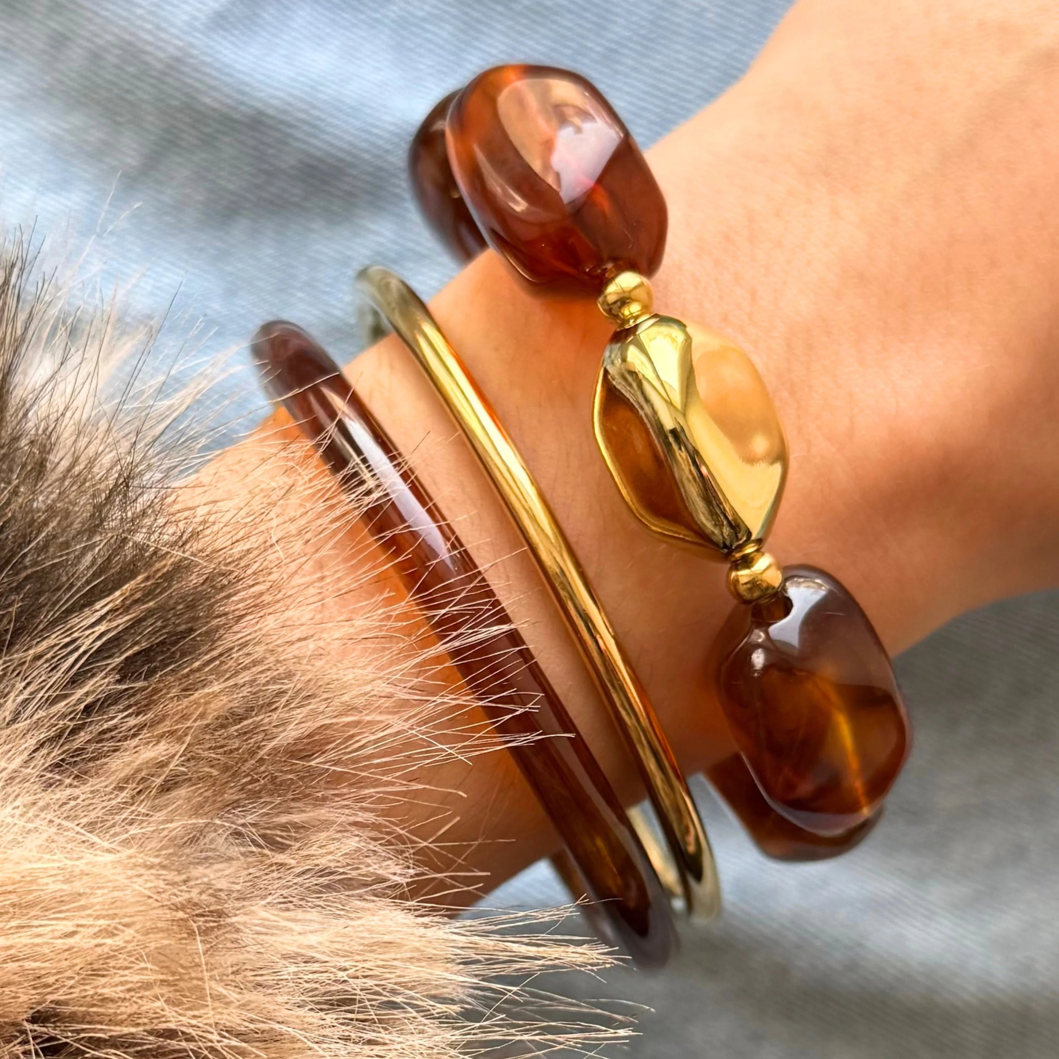 Vue latérale du bracelet à grosses perles porté avec un manteau en fausse fourrure, style chic hivernal.