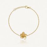 Bracelet fin en acier inoxydable doré, chaîne et pendentif fleur texturée, sur fond clair.