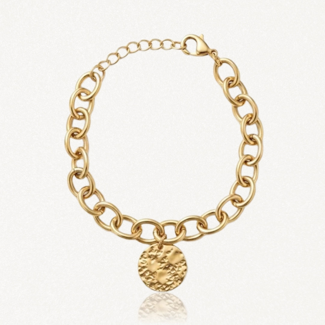 Bracelet doré à maillons ovales épais, avec un fermoir mousqueton et une breloque ronde texturée martelée.