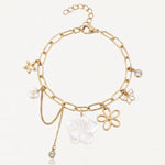 Bracelet chaîne doré à maillons allongés avec 6 pendentifs : grande fleur nacrée, 2 fleurs dorées, étoile, perle et 2