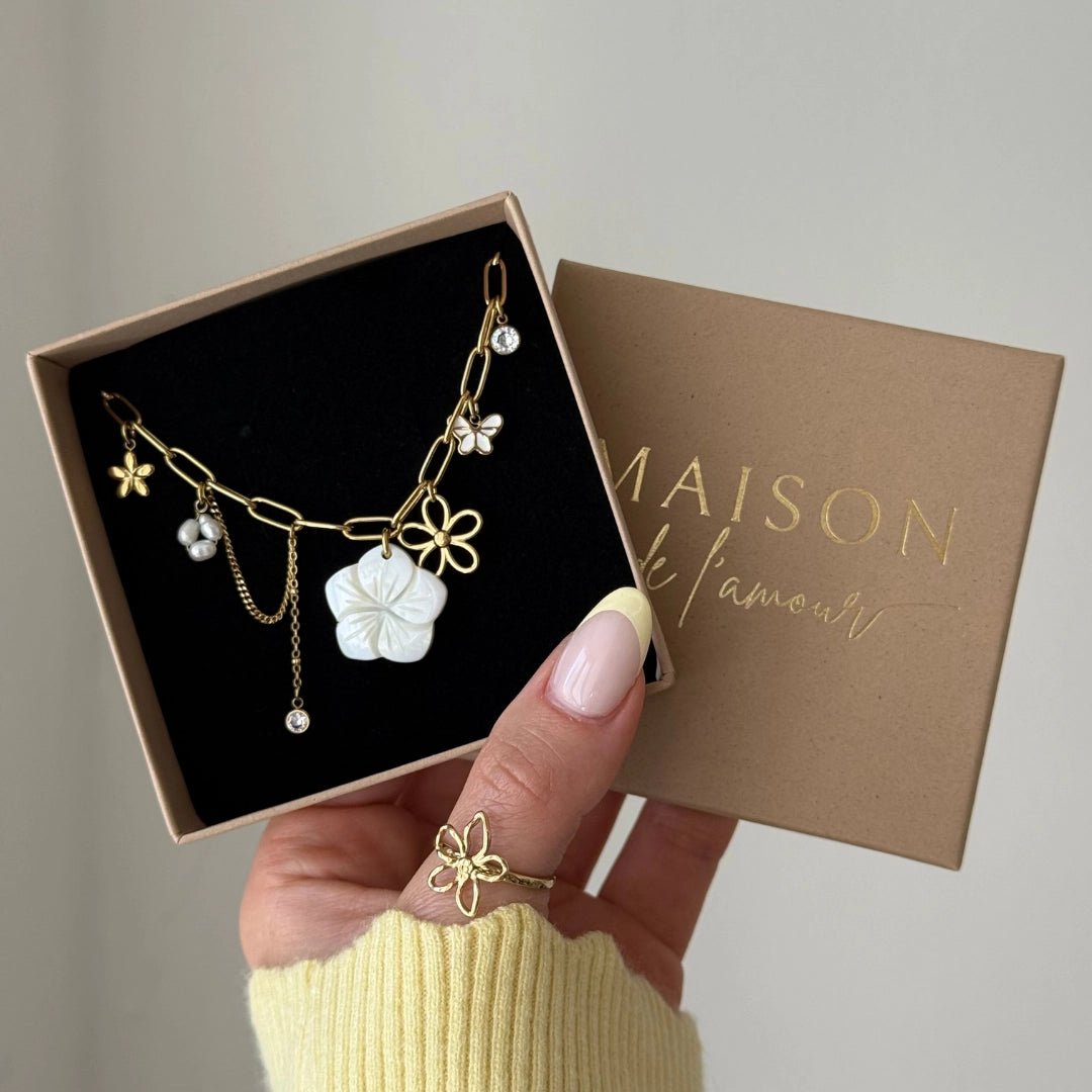 Bracelet chaîne acier inoxydable doré avec charms fleurs nacre, perles, papillon et cristaux, dans sa boîte cadeau.