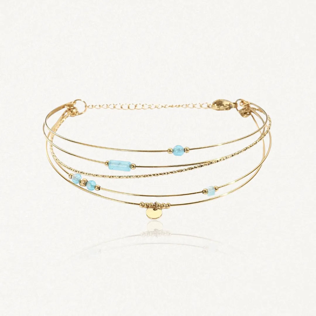 Bracelet semainier 4 fils en acier inoxydable doré orné de pierres naturelles bleu clair, de perles dorées et d'une pastille