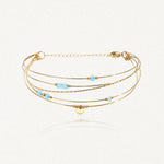 Bracelet semainier 4 fils en acier inoxydable doré orné de pierres naturelles bleu clair, de perles dorées et d'une pastille