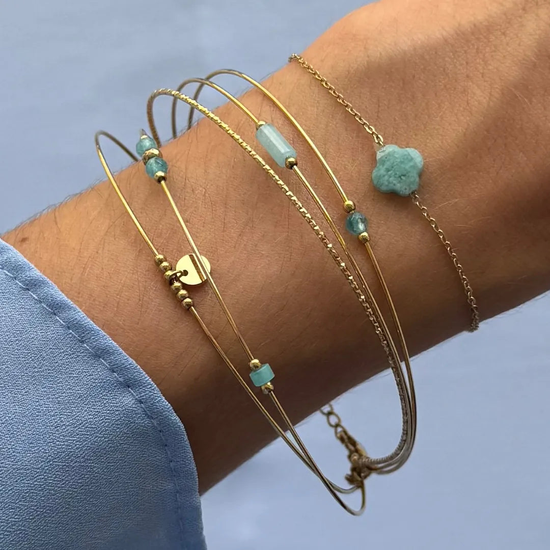 Bracelet multirangs en acier inoxydable doré orné de pierres naturelles bleu-vert variées et petites billes dorées, sur un