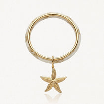 Bracelet jonc en acier inoxydable motif marbre blanc et doré avec pendentif étoile de mer dorée texturée.